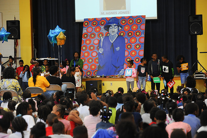 Students stand in front of a colorful mural of Mary Agnes Boswell Jones